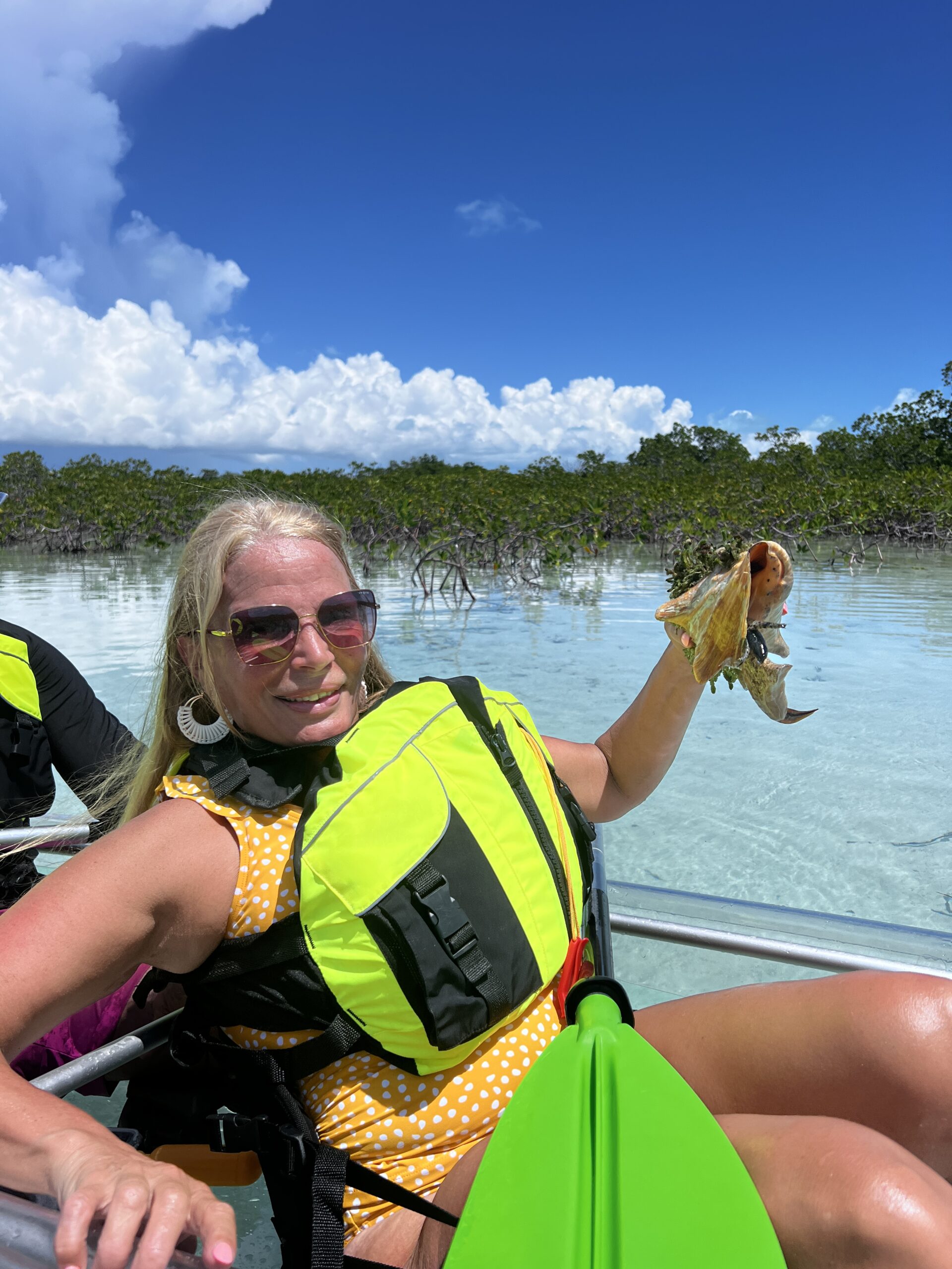 Guest holding a conch during a clear kayak mangrove tour