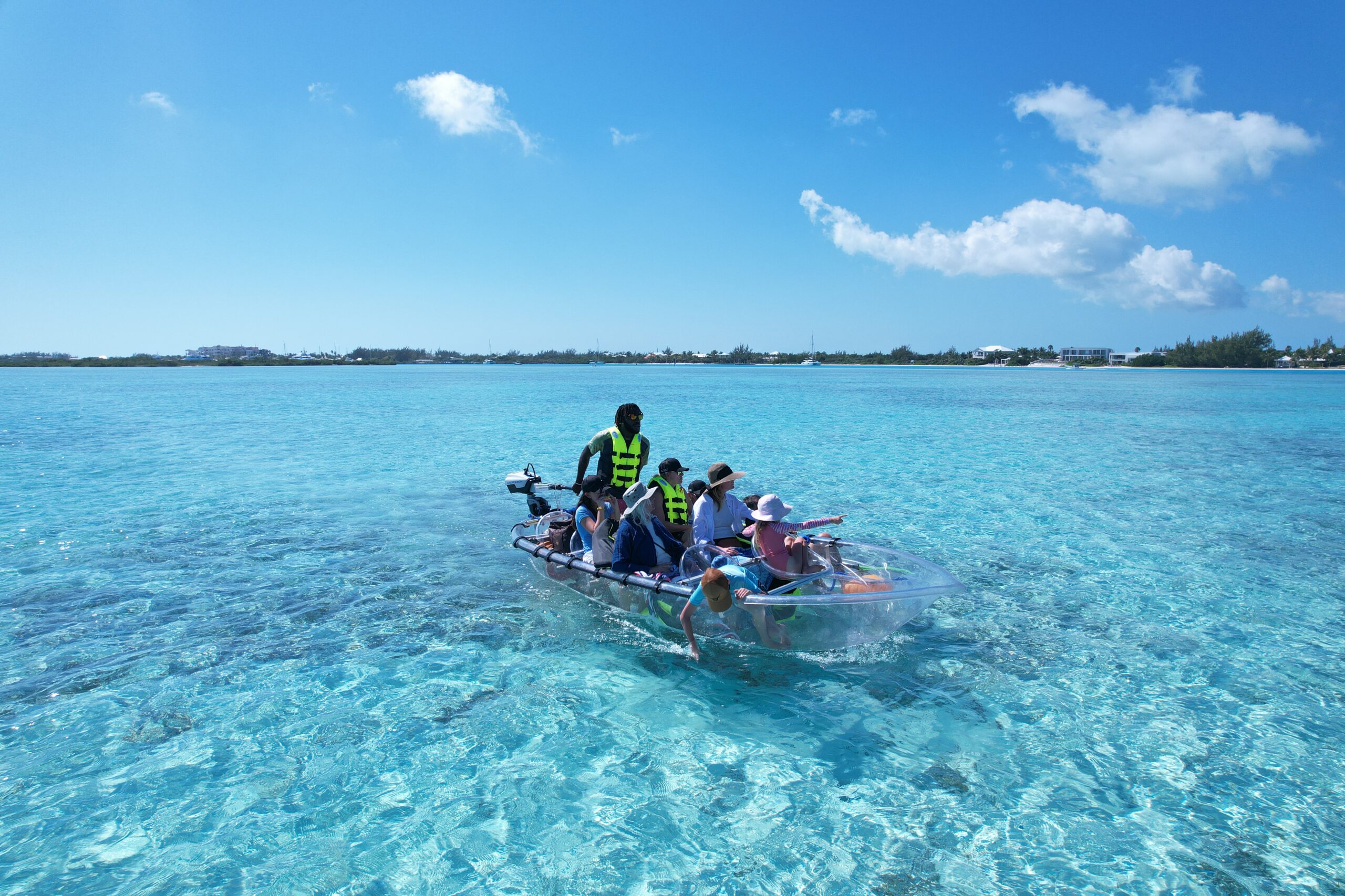 Guests riding through shallow Mangrove Cay water in the motorized clear kayak